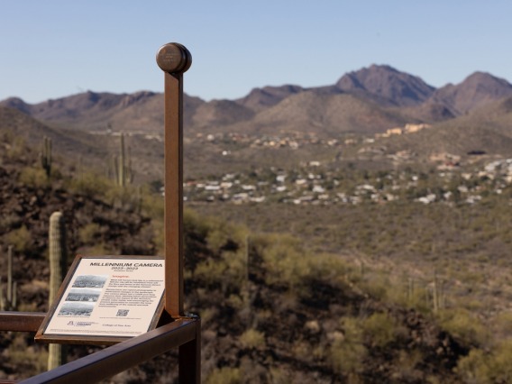 Image of a sign and art installation looking out at the mountains from Tumamoc Hill