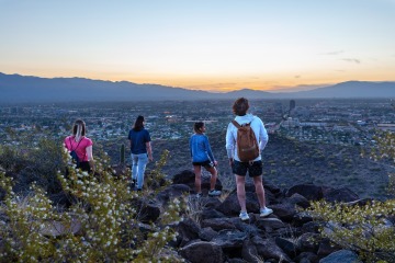 Four students look out toward the horizon from Tumamoc Hill